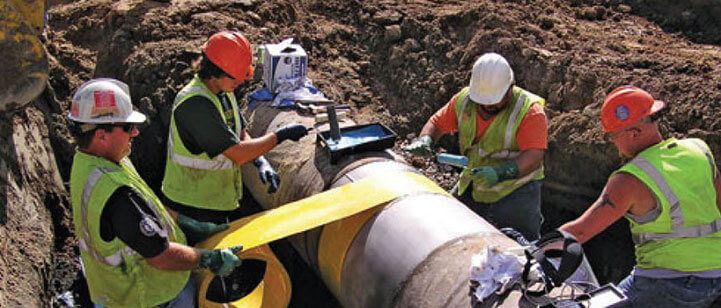 Workers wrapping a pipe.