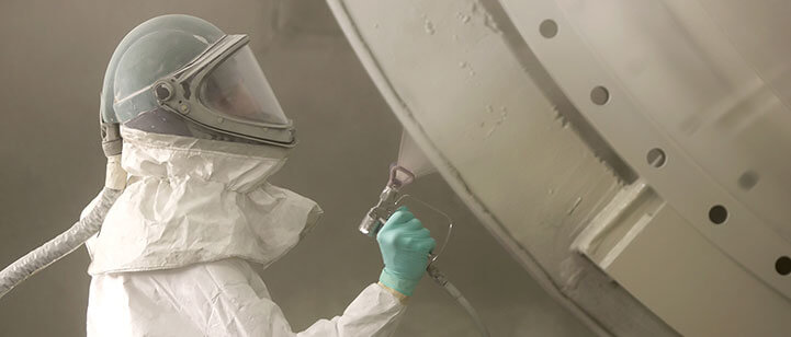 A man in a hazmat suit using AirTech Spray.