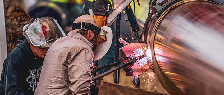 A worker welding a pipe. 