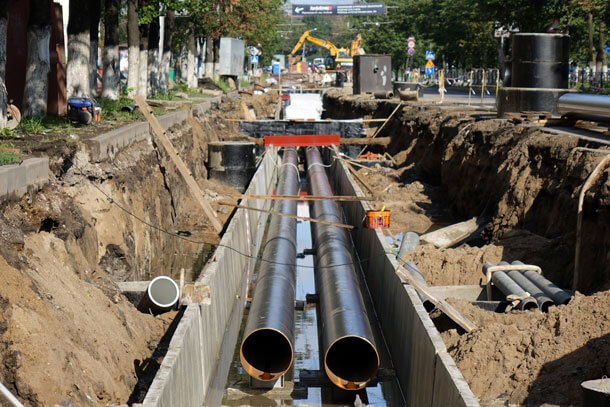 Two pipes being laid underground on a city street.