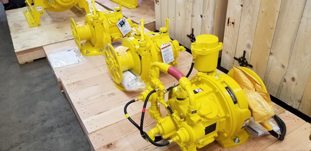 Three electric winches lined up on wooden pallet. palettes