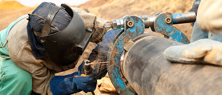 Three workers welding a brass pipe.